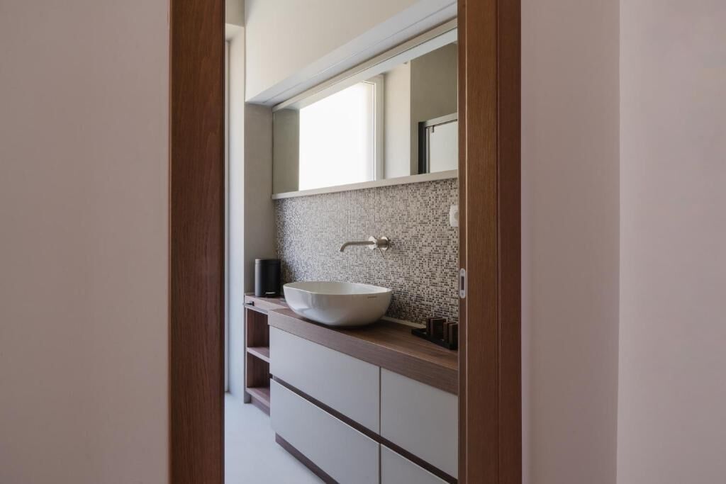 A modern bathroom with a large vessel sink, a mirror above it, and a tiled backsplash.