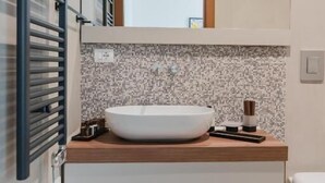 Un baño moderno con un lavabo de pedestal, una ventana pequeña sobre el espejo y un perchero para toallas.