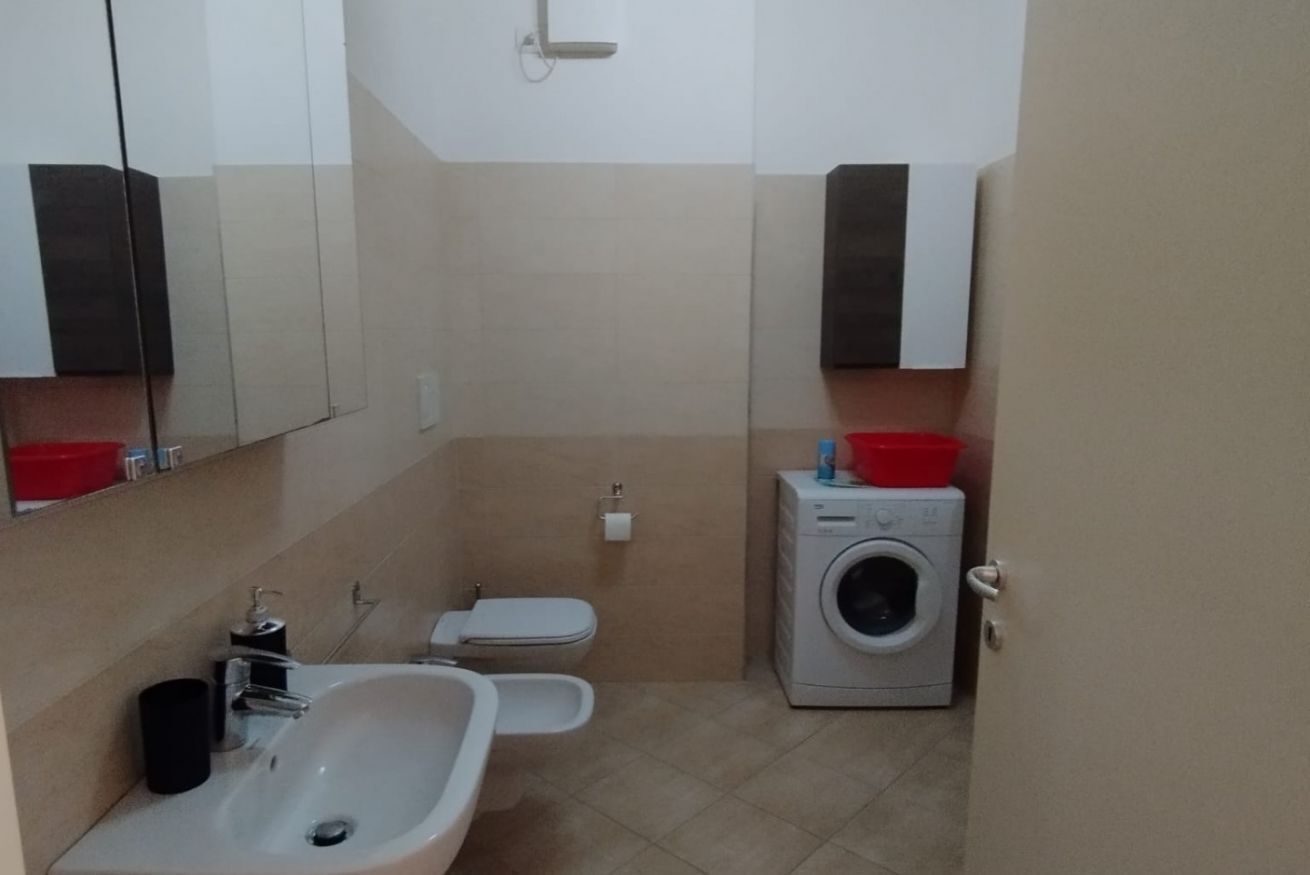 A compact bathroom with a sink, toilet, and washing machine.