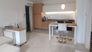 Eine moderne Küche mit weißen Schränken, einer Holz Arbeitsplatte und einem Barhocker.