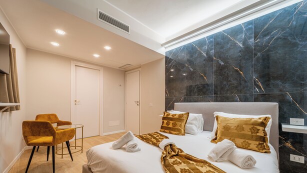 Ein Hotelzimmer mit einem Bett, zwei Sesseln, einem kleinen Tisch und einem großen Fenster mit Blick.