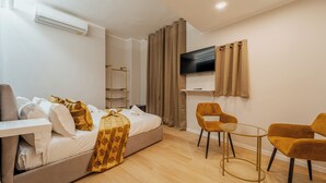Ein modernes Hotelzimmer mit einem Bett, einem Fernseher, einem kleinen Tisch und zwei Stühlen.