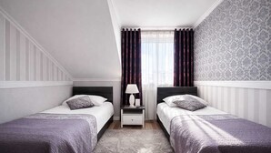 A twin bedroom with two beds, a nightstand, a lamp, and a patterned rug. - Noclegi Komfort  (Lublin)