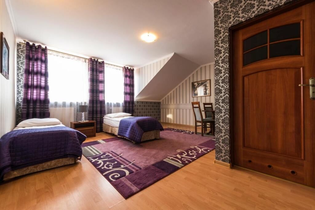 Un dormitorio con dos camas, una puerta de madera y una ventana con cortinas.