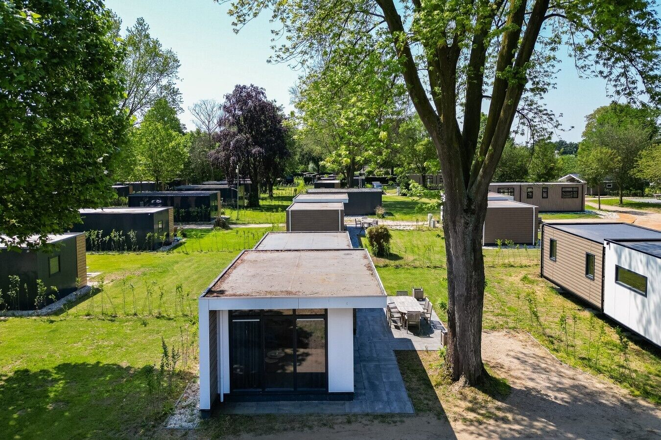 Un barrio residencial con casas modernas y compactas, cada una con techo plano y un pequeño jardín delantero.