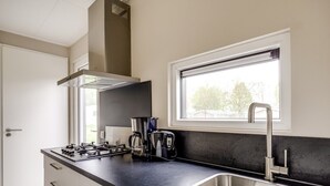 Una cocina moderna con estufa a gas, cafetera y pileta de acero inoxidable.
