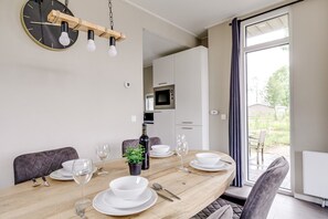 Un coin repas avec une table en bois dressée pour quatre personnes, une plante en pot et une bouteille de vin.