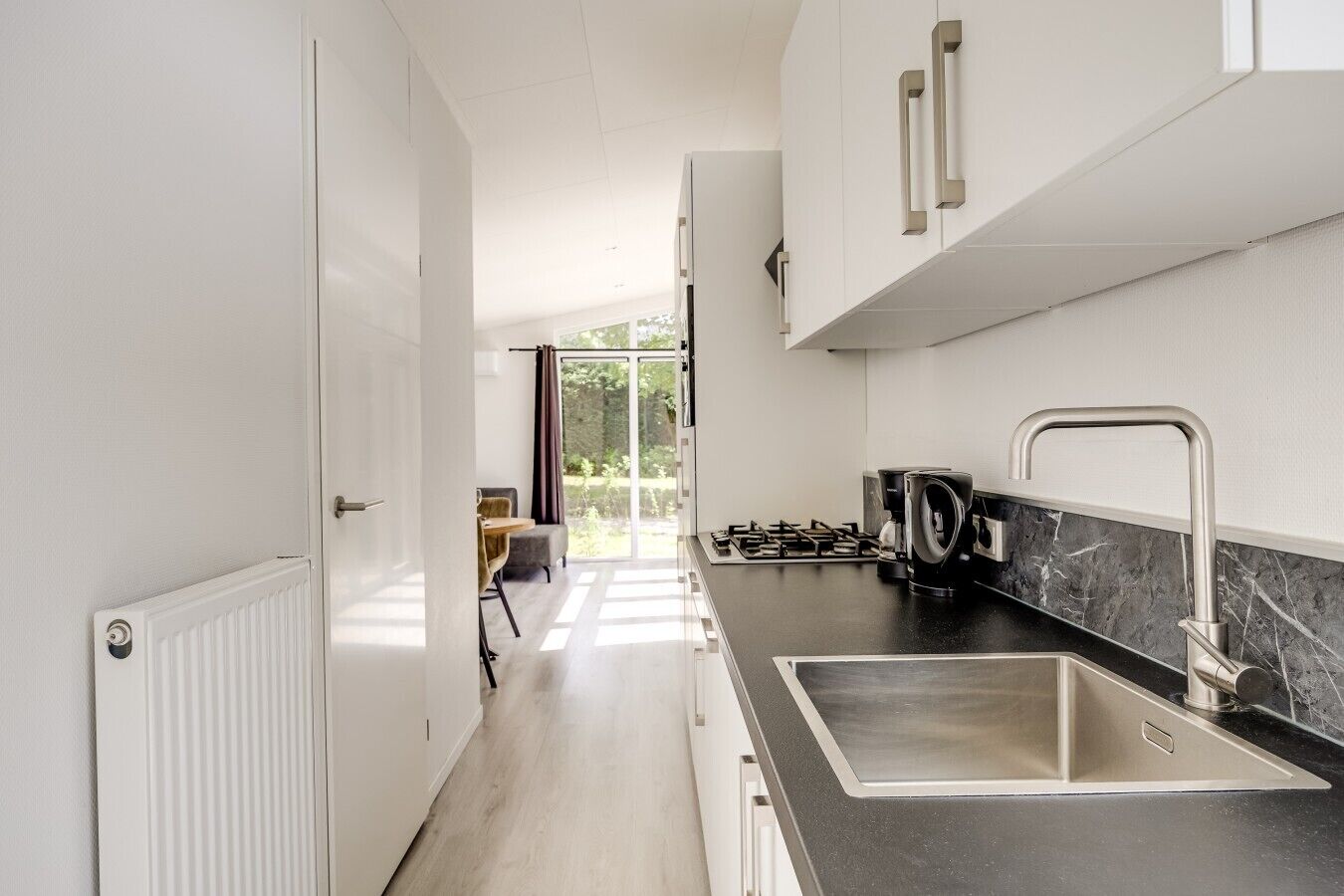 Une cuisine moderne dotée d’un plan de travail noir, d’un évier en acier inoxydable et d’une cuisinière à gaz.