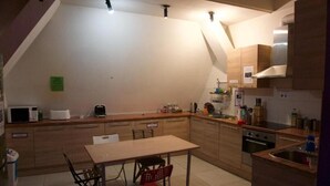 Een compacte keuken met een eettafel, stoelen, een magnetron, een broodrooster en een spoelbak.
