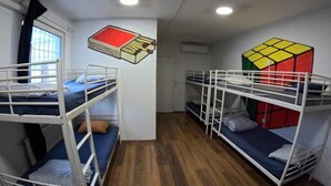 Een kamer met stapelbedden, een raam met gordijnen en een lamp.
