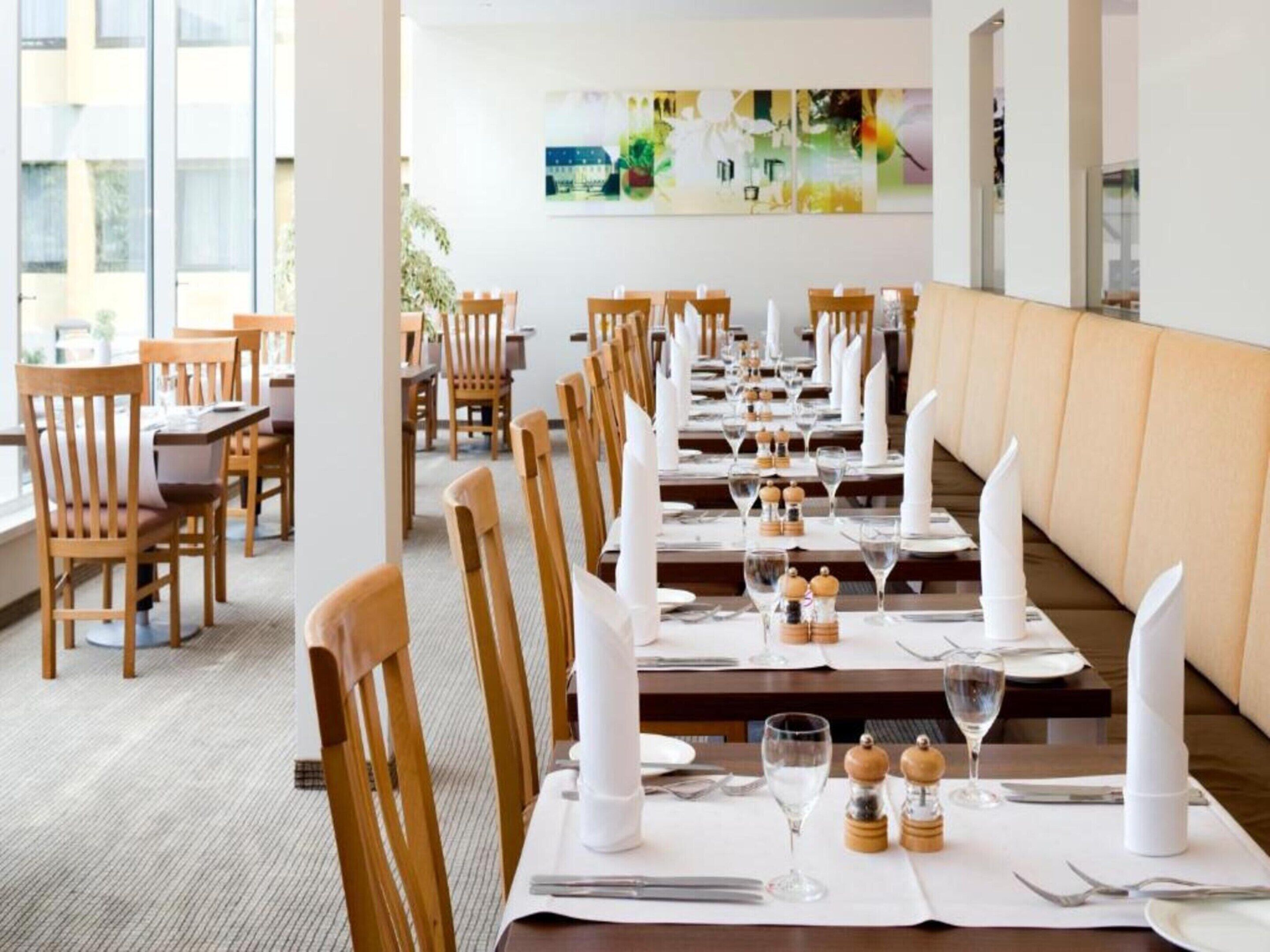 Un restaurante con mesas largas dispuestas para comer, sillas de madera y una decoración de estilo moderno.