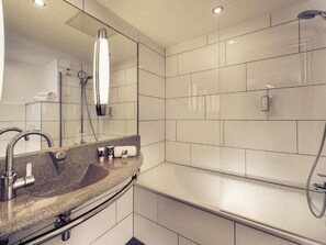 A modern bathroom with a large mirror, a granite countertop, a bathtub, and a shower. - Sunday Hotel Saarbruecken Sued Triple Room (Saarbrücken)