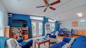 Uma sala de estar com televisão, estante e móveis azuis.