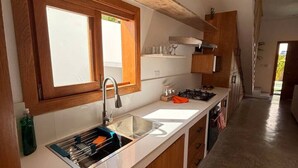 Une cuisine moderne avec des meubles en bois, un évier en acier inoxydable et une fenêtre située au-dessus de l’évier.