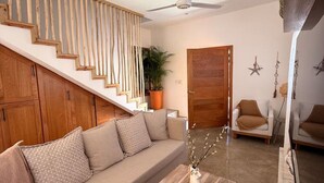 Un salon moderne avec un escalier en bois, un canapé, une table basse et un ventilateur de plafond.