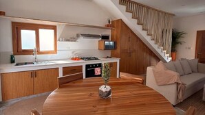 Une cuisine moderne dotée d’un îlot central, de meubles en bois, d’une cuisinière intégrée et d’un escalier menant à un niveau supérieur.