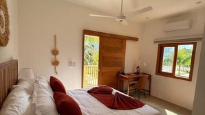 Une chambre avec un lit, un bureau, une chaise, un ventilateur de plafond et une fenêtre.