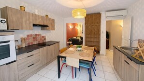 Eine moderne Küche mit Holzschränken, einem Esstisch mit Stühlen und einer Hängelampe.
