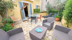 Eine Terrasse im Freien mit Korbmöbeln, einem Tisch und Kübelpflanzen.