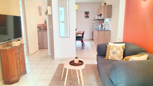 Ein Wohnzimmer mit einer Couch, einem Fernseher und einem kleinen Tisch mit einer Pflanze.
