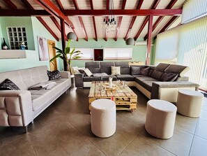 Un salon spacieux avec un grand canapé d’angle, une table basse en bois et une plante en pot.