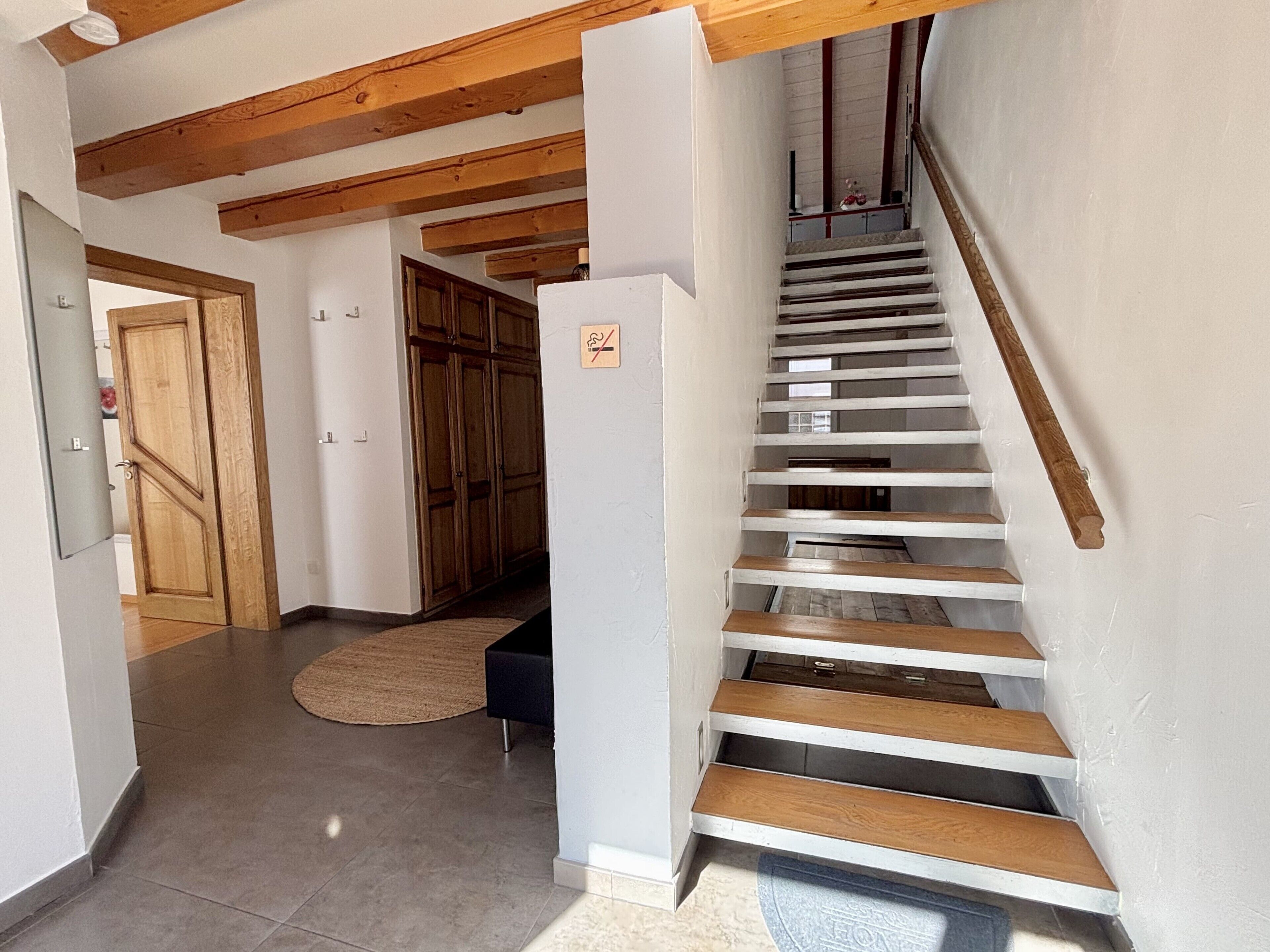 A staircase with wooden steps and a handrail, leading to a landing with a door and a small cabinet.