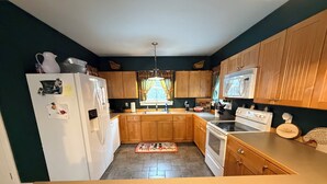 A kitchen with wooden cabinets, a white refrigerator, a stove, and a microwave. - Lovely 5-bedroom house in Londonderry perfect for your getaway (Londonderry)