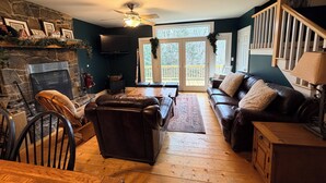A cozy living room with a fireplace, leather sofa, wooden flooring, and a staircase. - Lovely 5-bedroom house in Londonderry perfect for your getaway (Londonderry)