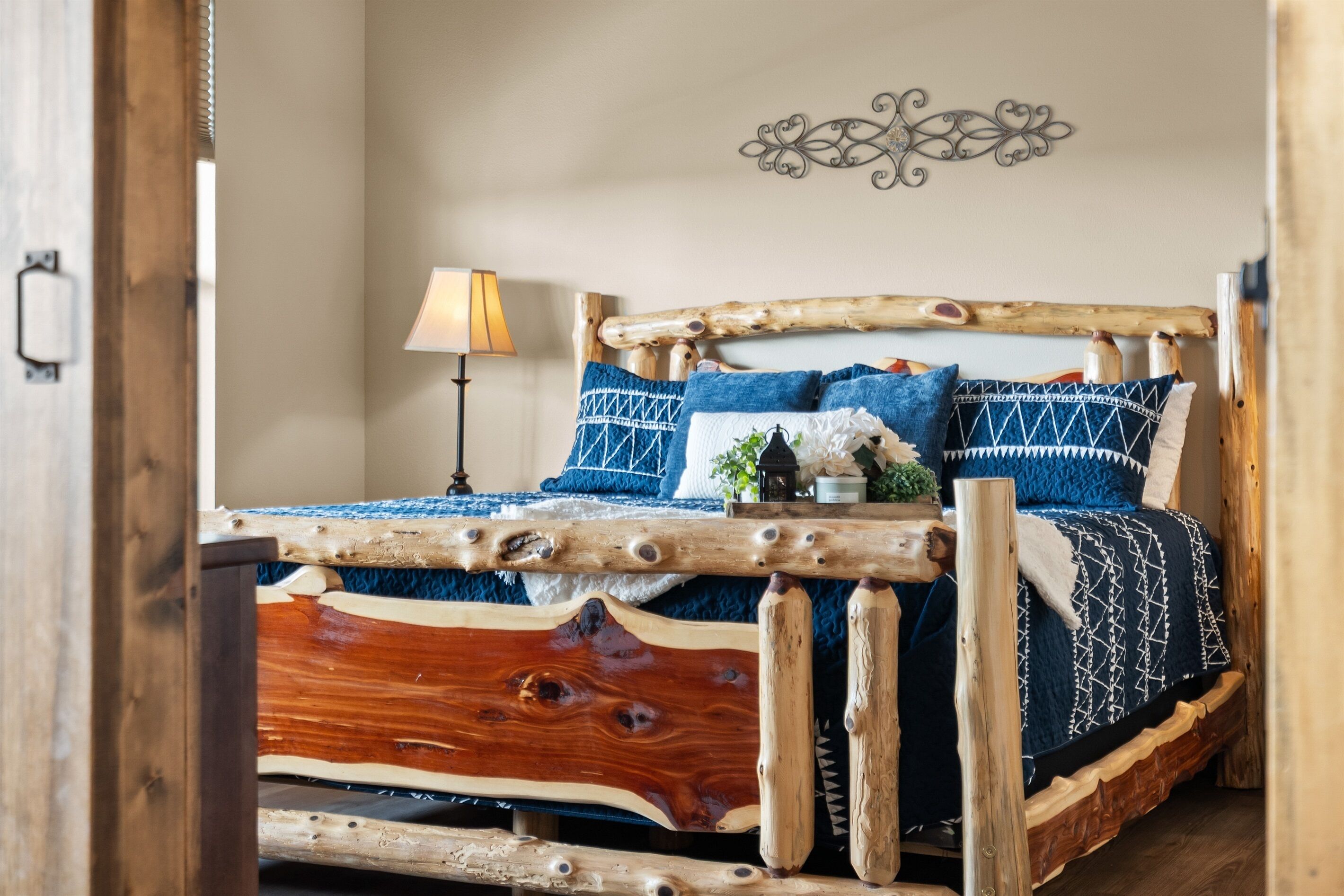 A rustic wooden bed with a unique design, a bedside lamp, and decorative wall art.