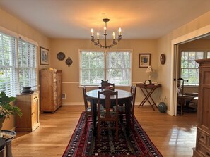 Un espace repas comprenant une table ronde, des chaises, un lustre et un tapis à motifs.