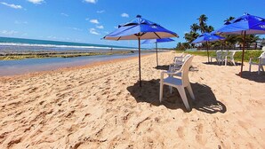 A beach with blue umbrellas and white chairs. - Bangalô à Beira-Mar - Piscina Gigante (Ipojuca)