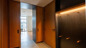 A hallway with wooden doors, a tiled floor, and a view into a room with a table and chairs. - LARCH HOUSE (Whitefish)