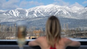 A person in a red swimsuit facing a snowy mountain landscape. - LARCH HOUSE (Whitefish)