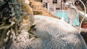 Ein Steinhaus mit Pool, einem weißen Metallstuhl und einer weißen Blumenkomposition.