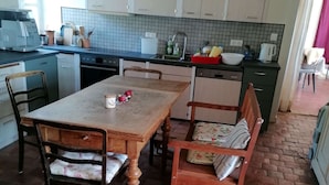 A kitchen with a dining table, chairs, and a brick floor. - Enter the wonderful world of nature and the stars of Morvan (Arleuf)