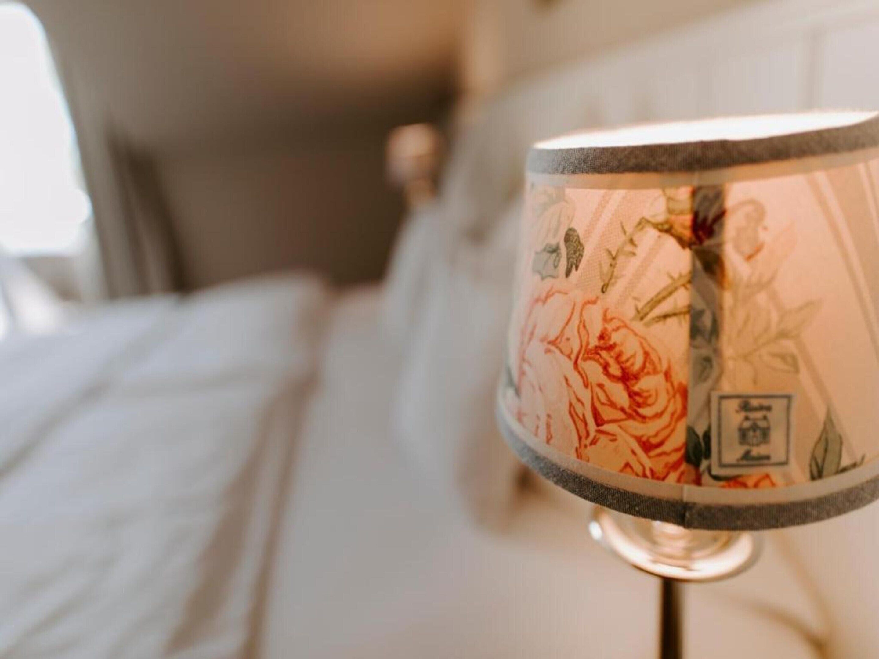 A lamp with a floral pattern on a bedside table.