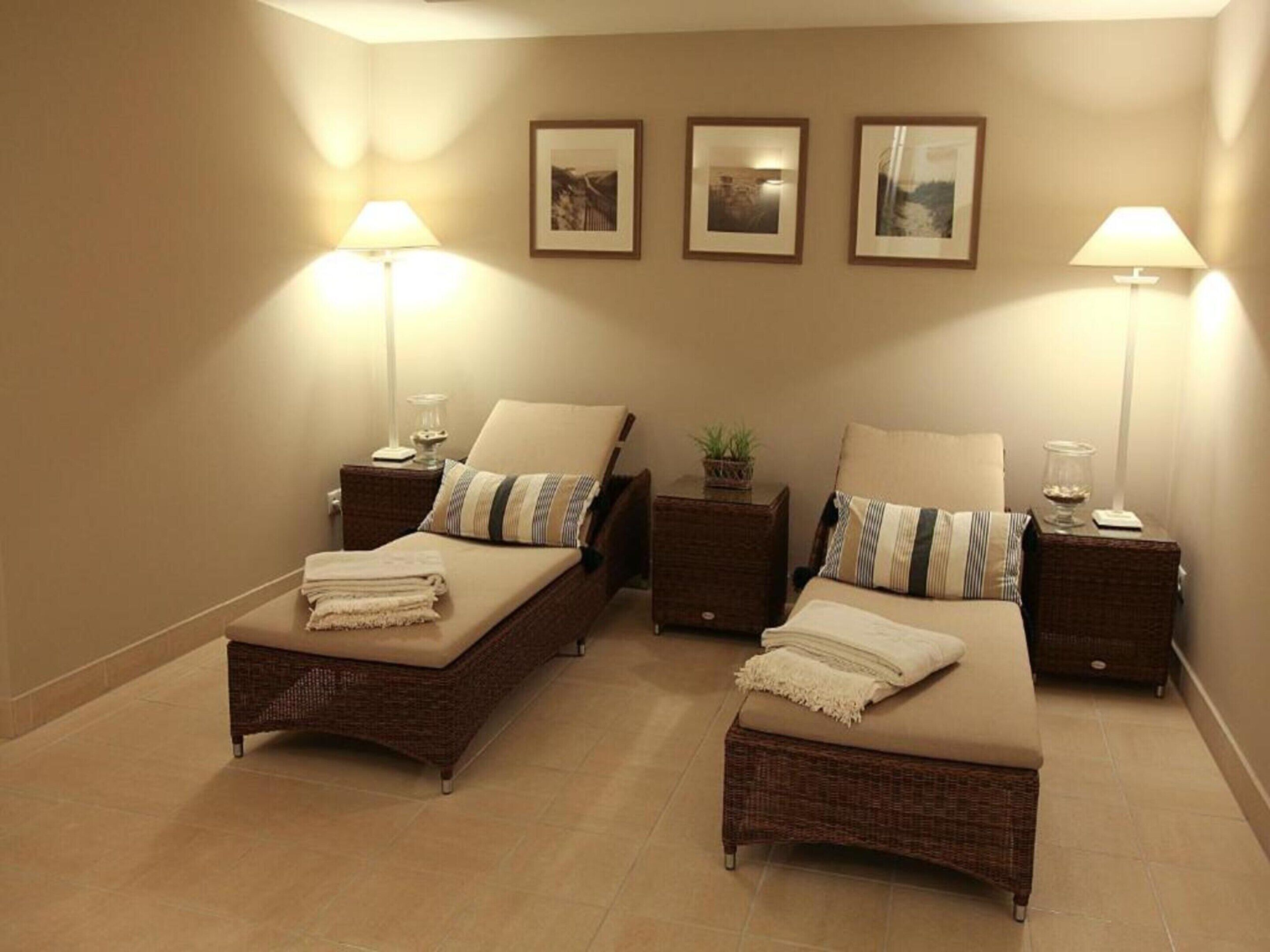 A hotel room with two single beds, each with a nightstand, a lamp, and a framed picture on the wall.