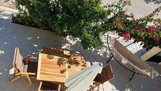 Un ensemble de mobilier de jardin en bois, comprenant des chaises et une table, entourĂ© de verdure et agrĂ©mentĂ© dâun hamac.