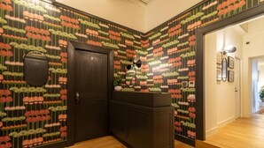 A hallway with patterned wallpaper, a dark wooden door, and a reception desk. - Relais Virgilio  (Rome)