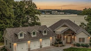 A two-story house with a garage, a front porch, and a driveway. - Luxe Manor - Heated Lakefront Pool, Lily Pad & More! (Sunrise Beach)