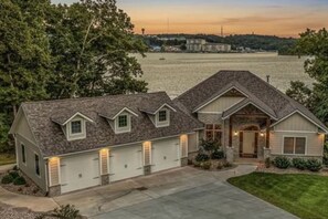 A two-story house with a garage, a front porch, and a driveway. - Luxe Manor - Heated Lakefront Pool, Lily Pad & More! (Sunrise Beach)
