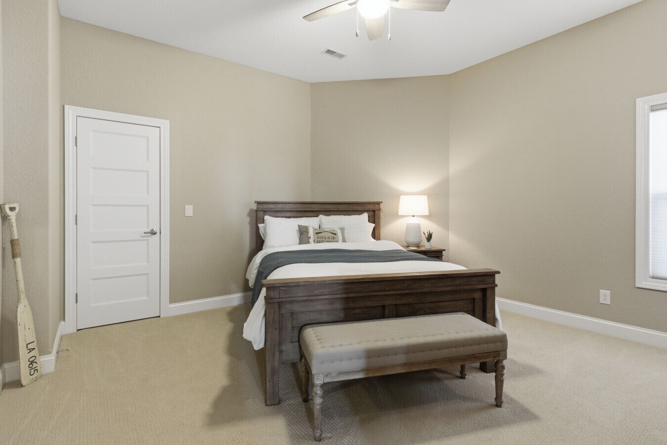 A bedroom with a bed, bedside lamp, and a window.