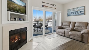 Sala de estar con chimenea, televisor, sofá y puerta corrediza de vidrio que da a un patio exterior.