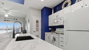 Una cocina moderna con armarios blancos, encimera de mármol y vistas a la ciudad.