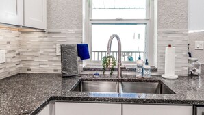 Eine Küche mit einer Arbeitsplatte aus Granit, einer Spüle aus Edelstahl und einem Fenster mit Blick.