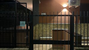 A gated area with a security camera, a wall-mounted air conditioning unit, and a tiled floor.