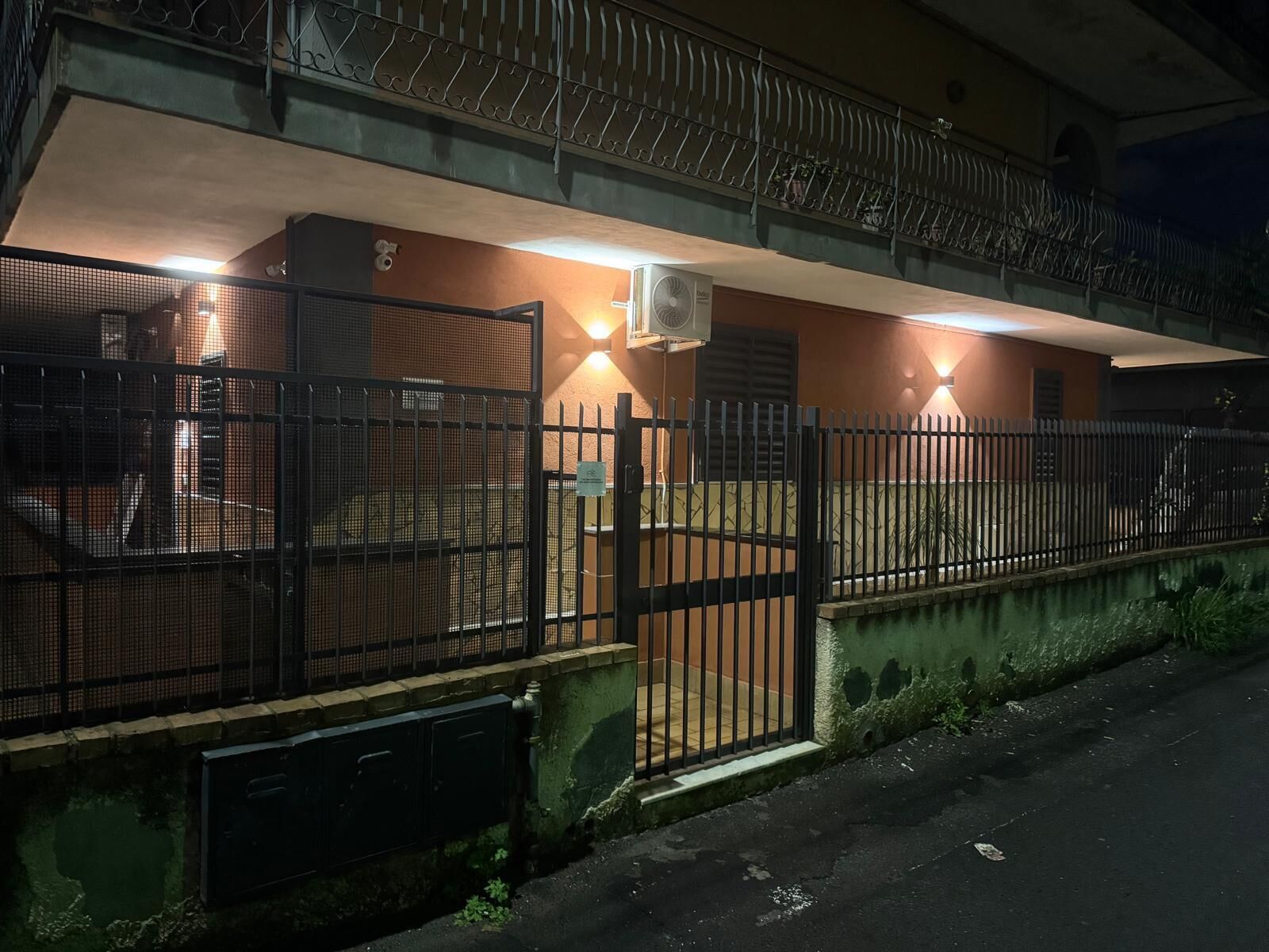 Un immeuble doté d’une entrée sécurisée par un portail, d’un balcon et d’un appareil de climatisation.