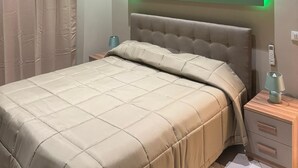A modern bedroom with a bed, nightstand, and a wall-mounted TV.