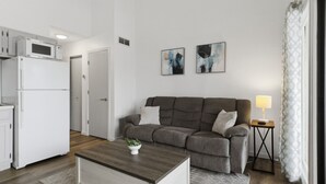 A modern living room with a grey sofa, a wooden coffee table, and a small side table with a lamp. - Lakeview for Two - Lakeside Pool & Top Floor! (Osage Beach)
