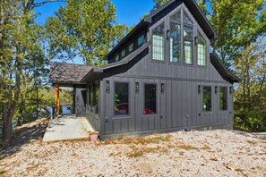 A two-story cabin with large windows and a covered porch.